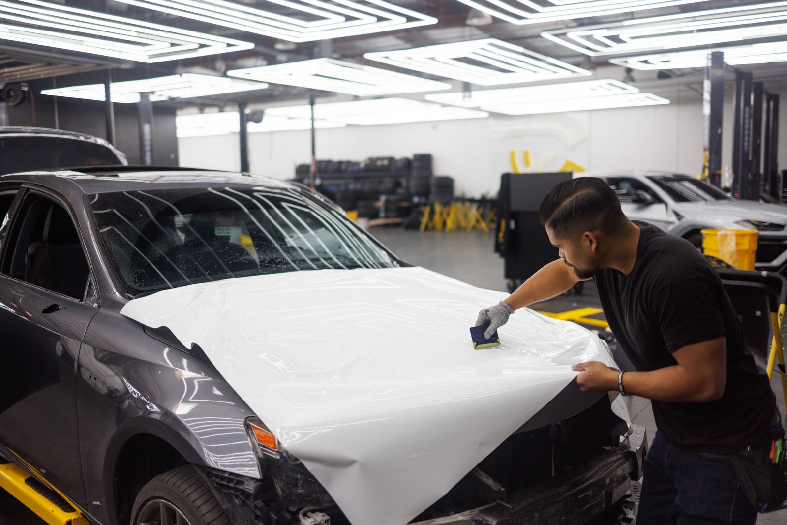 Installer squeegeeing film onto a car hood