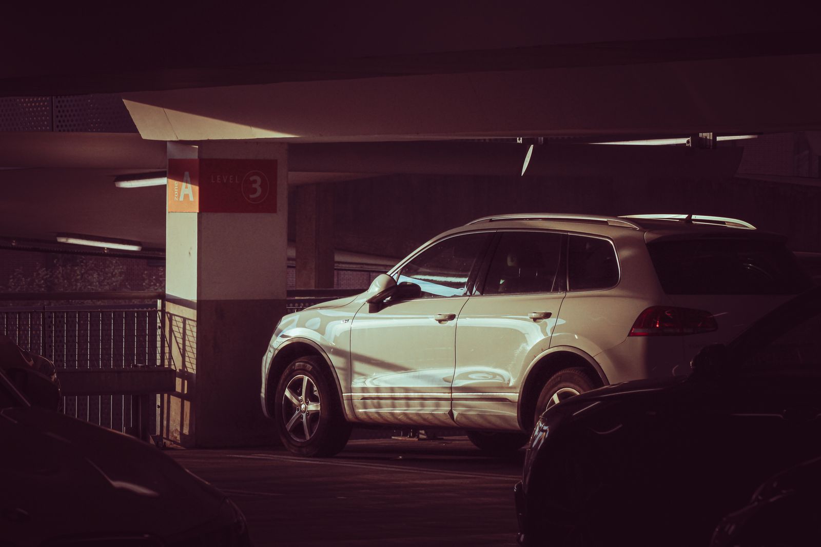White SUV parked in a garage with dramatic light
