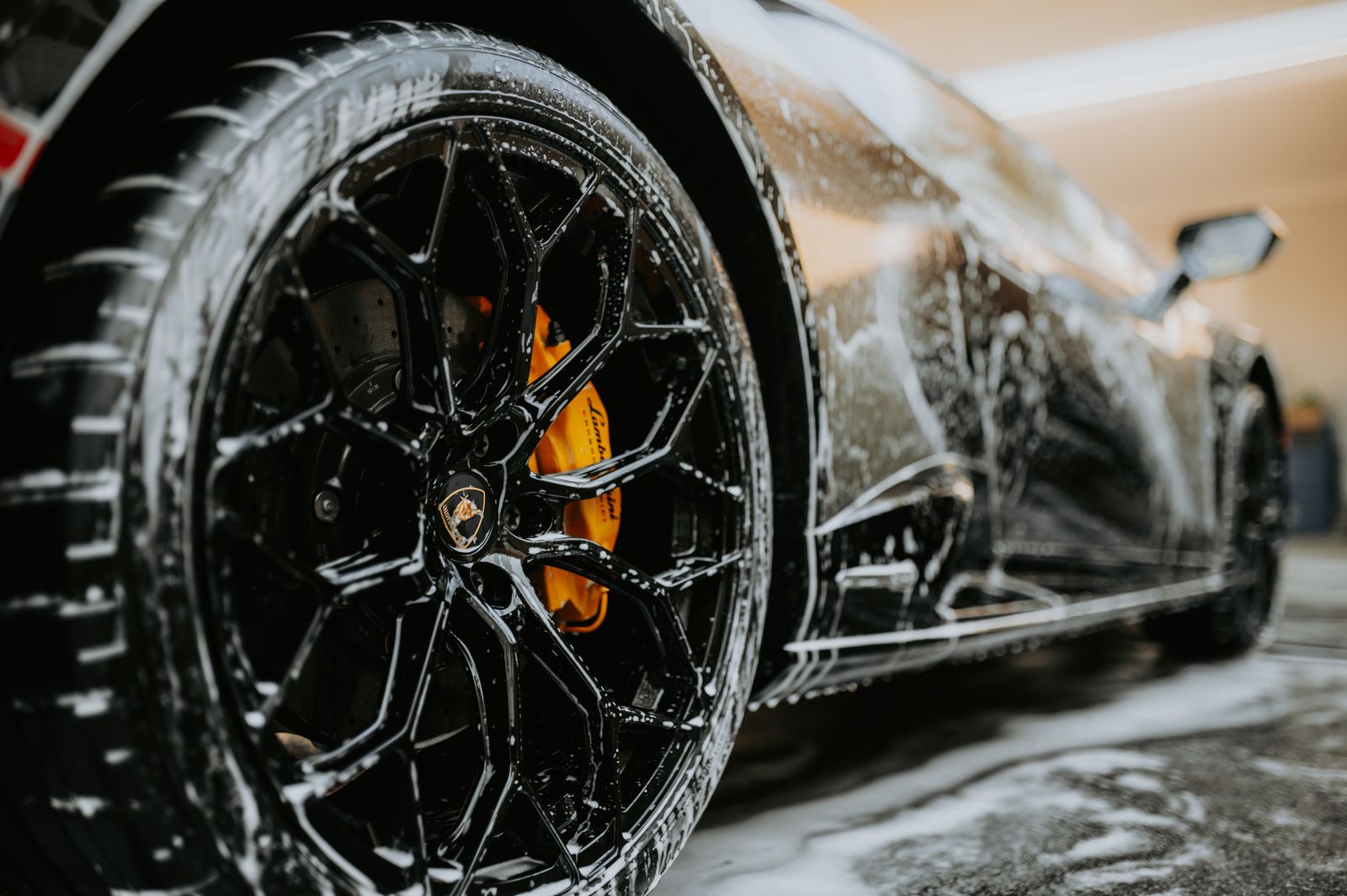 Close-up of a car wheel covered in soap during a wash