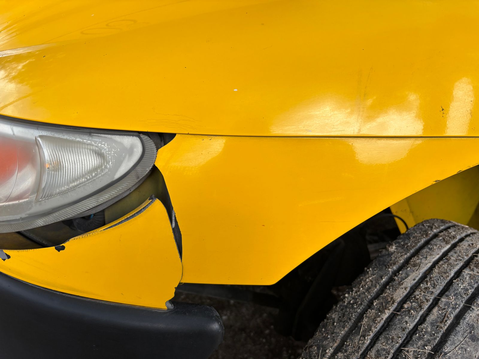 Unprotected front bumper and headlight with chips and impact damage