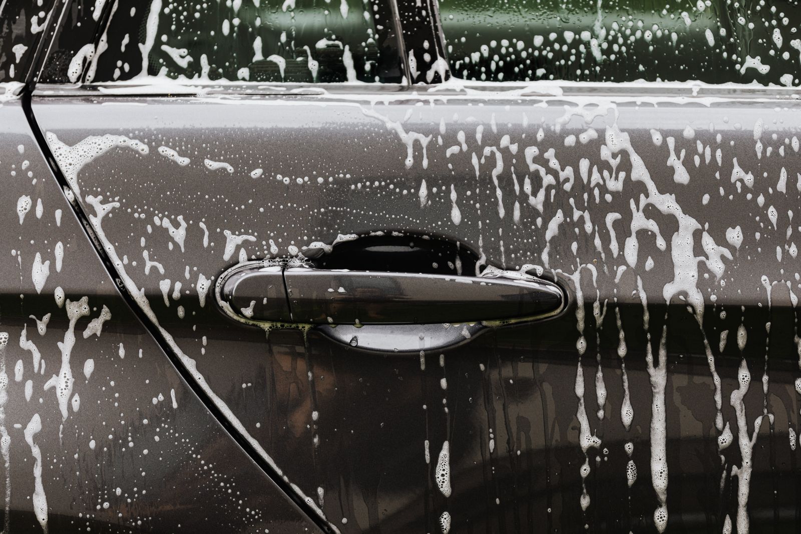 Soap foam on a black car door during a wash